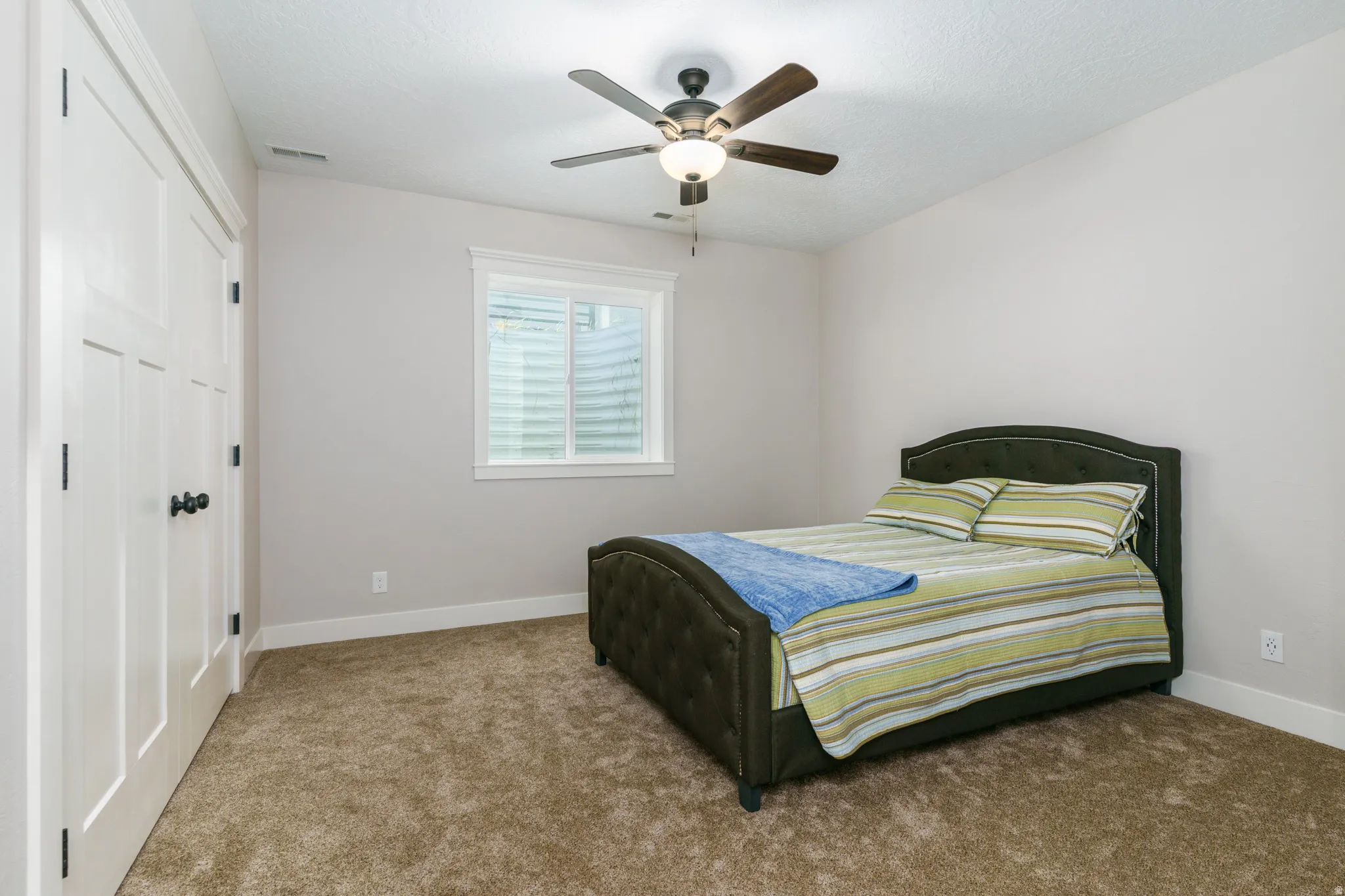Neutral wall color, carpeted flooring, a ceiling fan with light fixture, and a window with blinds