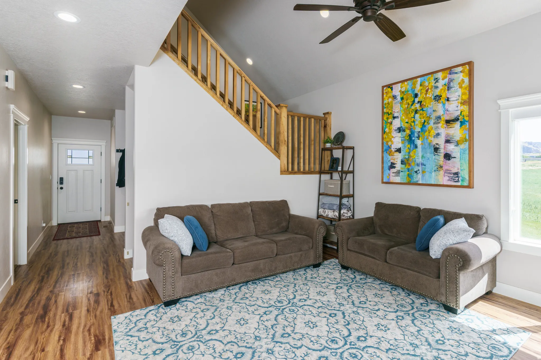 Open-concept living space featuring wood-finish flooring, a contemporary ceiling fan, and a light-filled window