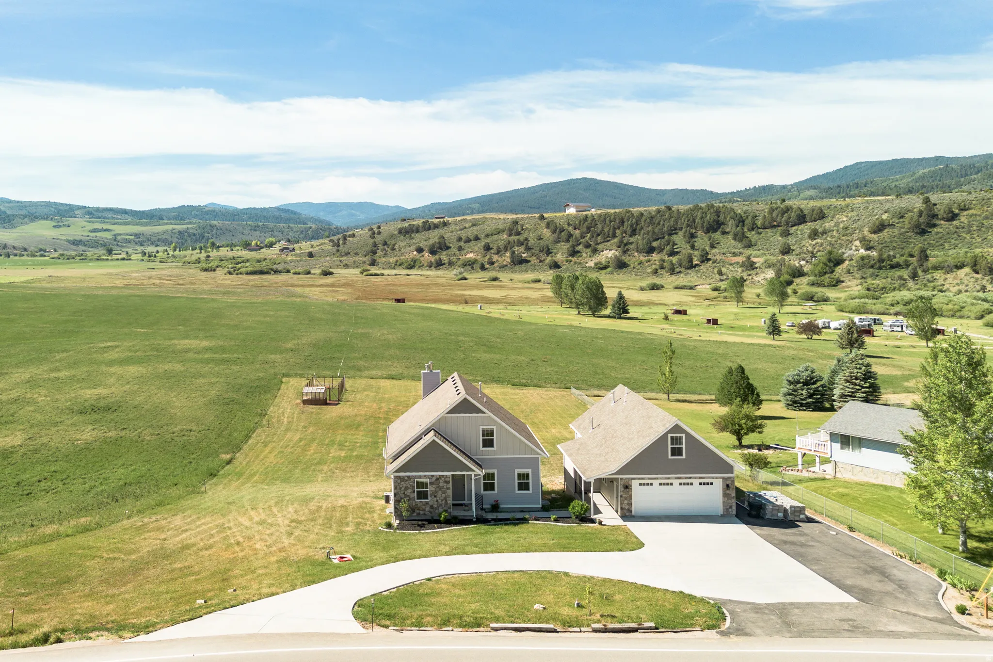 Two-story residence with a two-car garage, gray siding, stone veneer accents, and a paved driveway