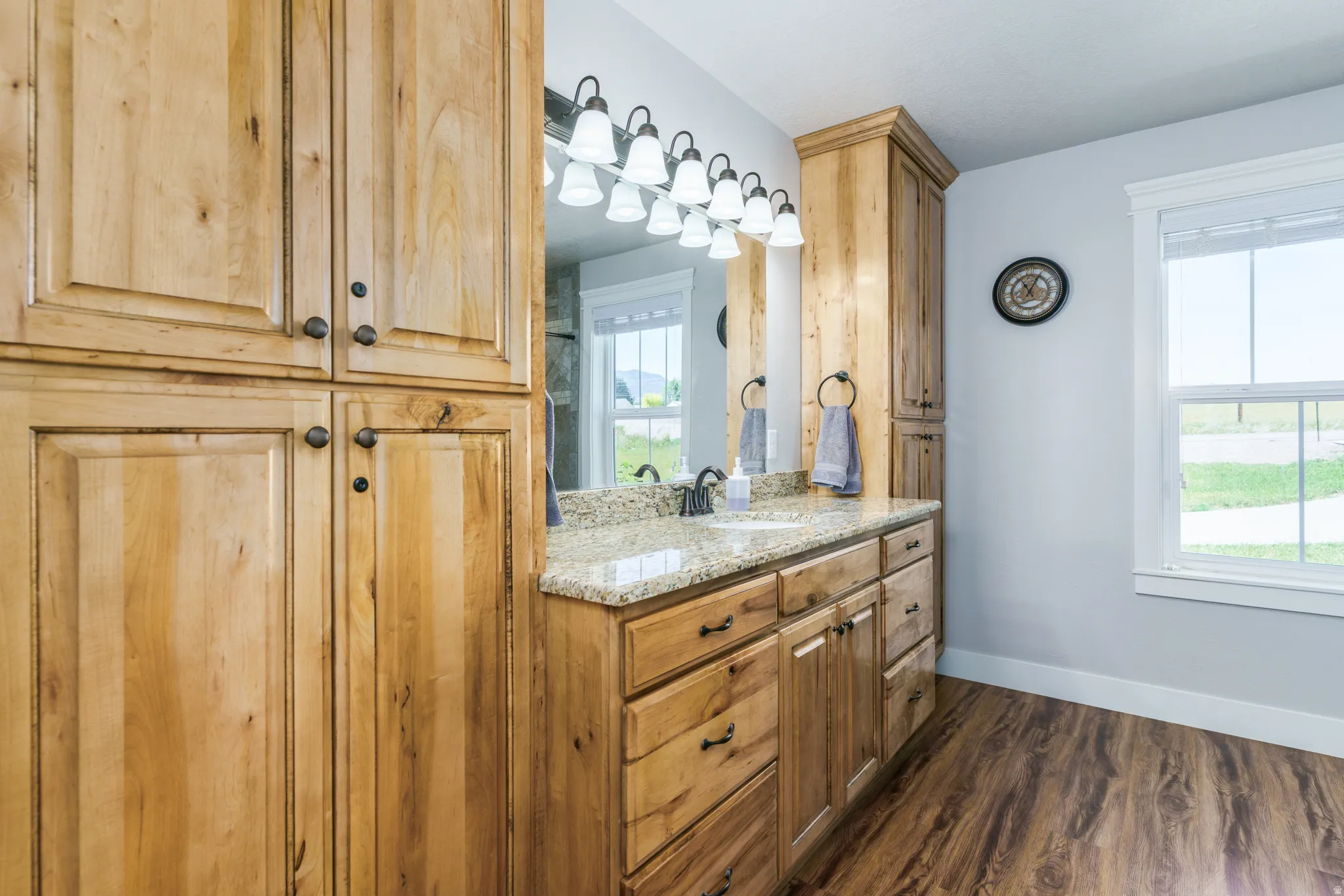 Dual vanity featuring a light-toned countertop and wood-finish cabinetry