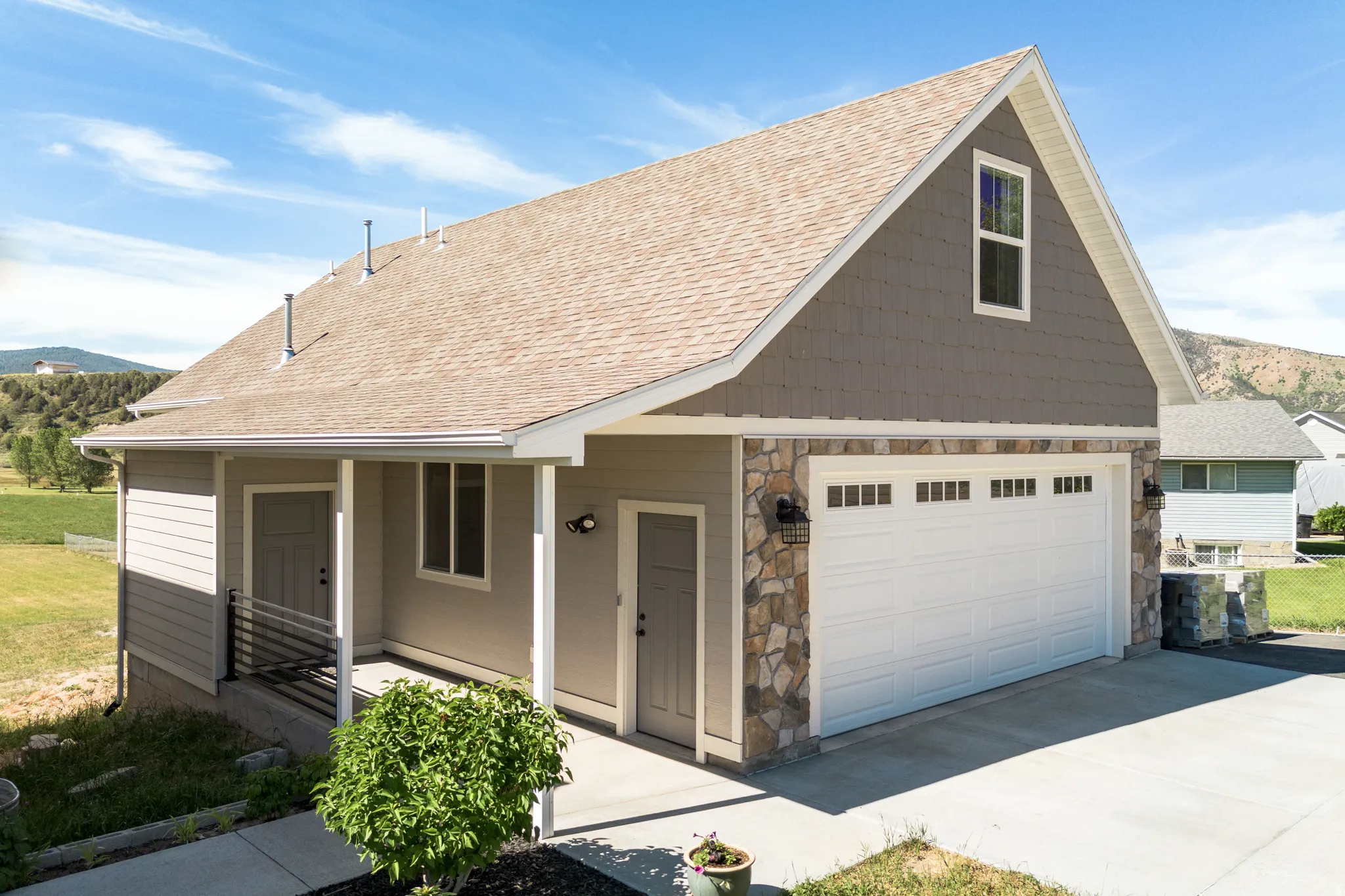 Multi-level exterior with a prominent two-car garage, stone veneer accents, and horizontal siding