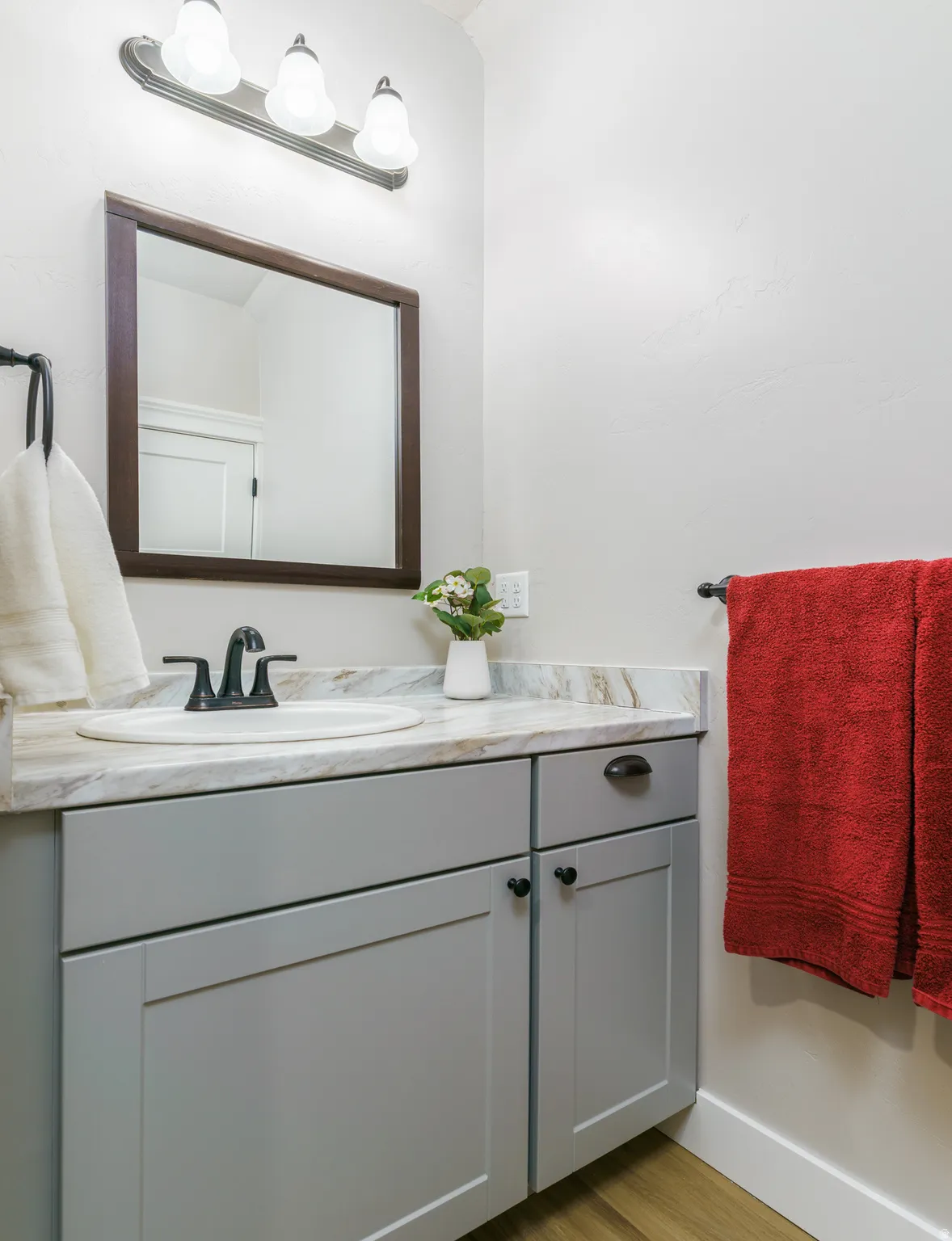 Light gray shaker-style vanity with black hardware, an integrated sink, and a stone-finish countertop