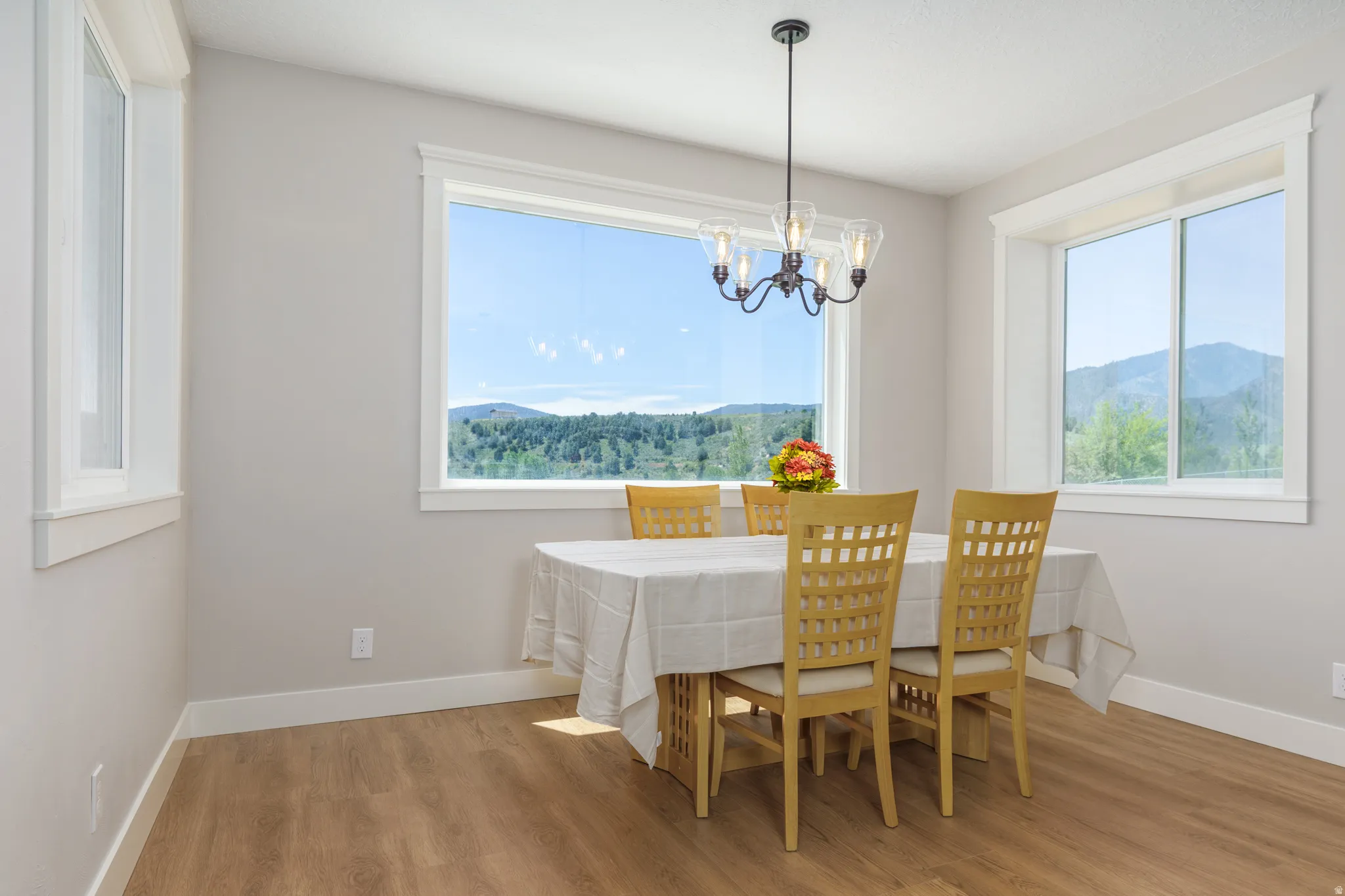 Wood-finish flooring, multiple windows, chandelier fixture, and neutral wall tones
