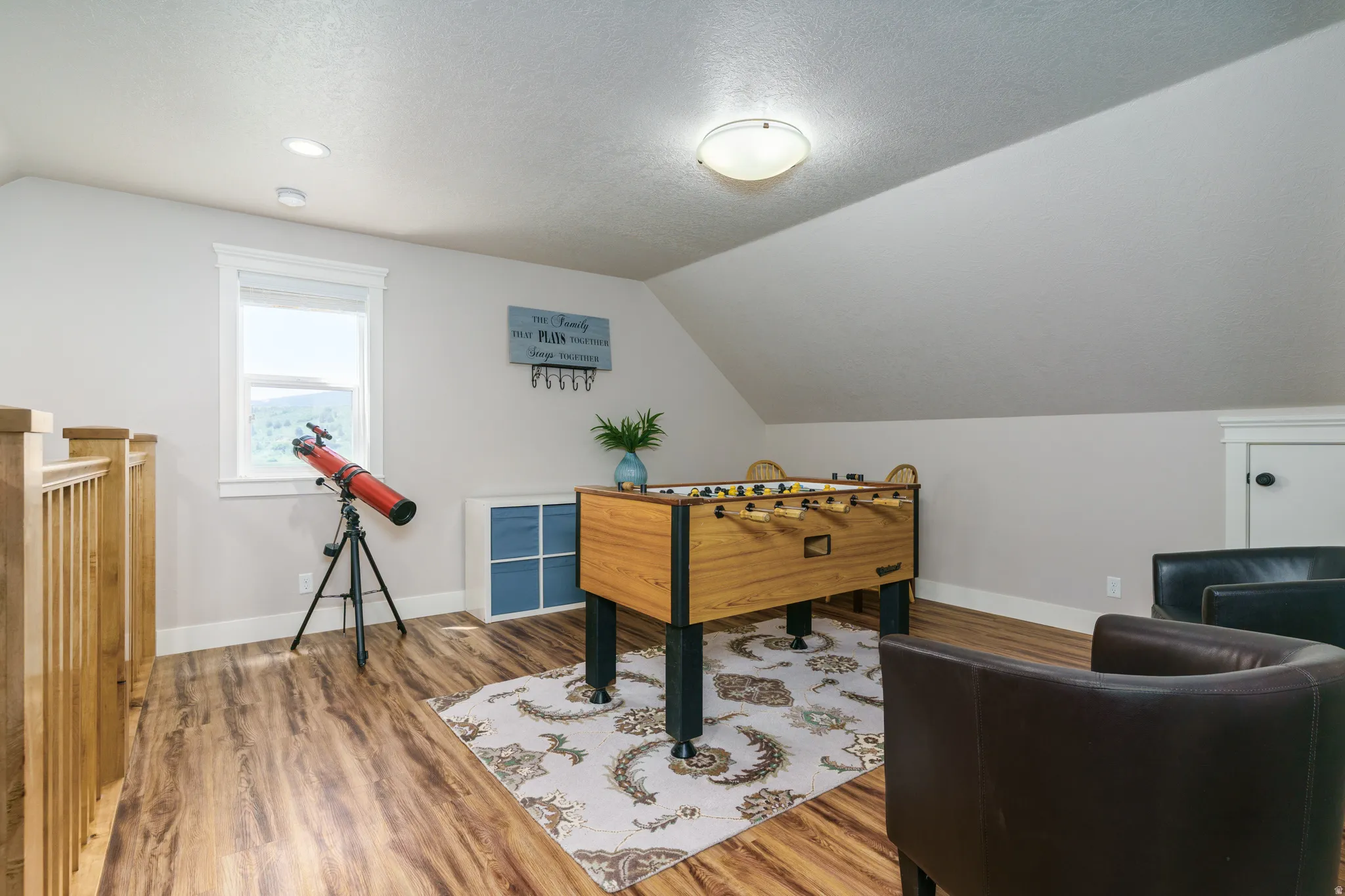 Sloped ceiling room featuring wood-finish flooring, a single window, and recessed lighting