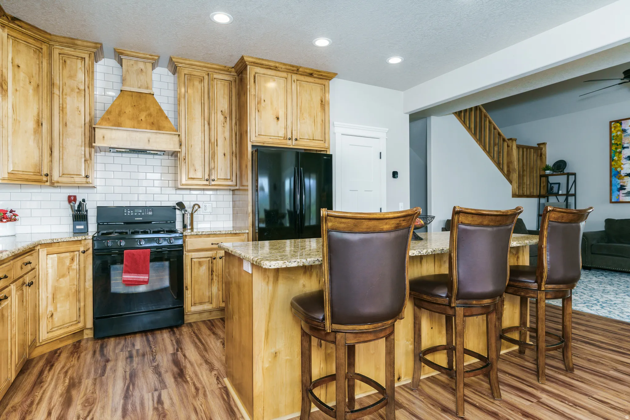 Kitchen featuring wood-finish cabinetry, subway tile backsplash, and a built-in kitchen island with counter seating