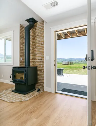 Wood-finish flooring with a brick accent wall, freestanding wood stove, and a glass-paned exterior door