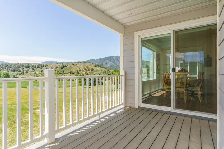 Outdoor deck with wood-finish flooring, white railing, and sliding glass door