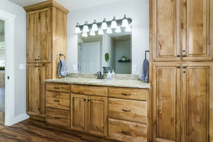 Wood-finish flooring with a multi-tone vanity, integrated sink, and stone-finish countertop