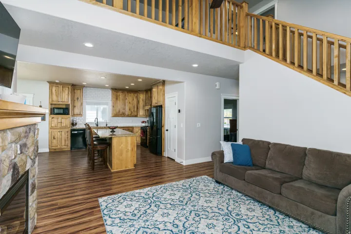 Open concept living area featuring wood-finish flooring and a stone-clad fireplace