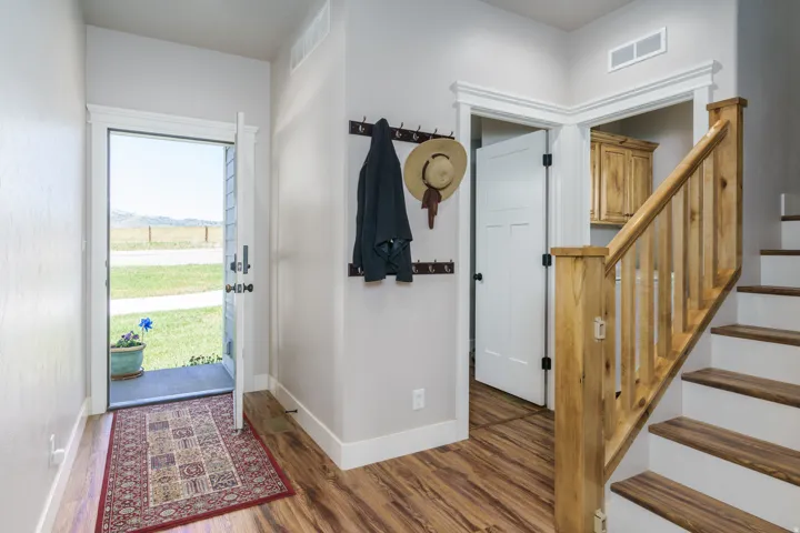 Wood-finish flooring throughout, white trim, and a natural wood staircase