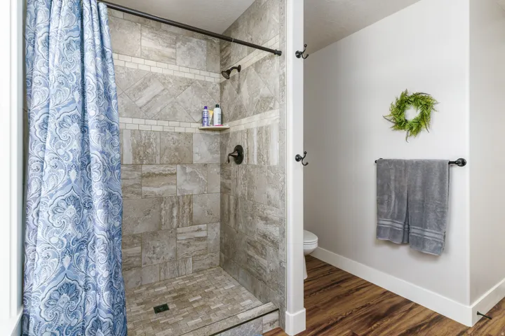 Tiled shower with a built-in corner shelf and bronze-finish fixtures