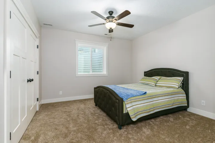 Neutral wall color, carpeted flooring, a ceiling fan with light fixture, and a window with blinds