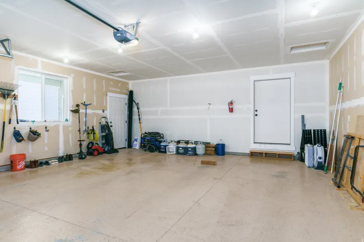 Garage with a window, single white door, an additional white door, and an automatic garage door opener