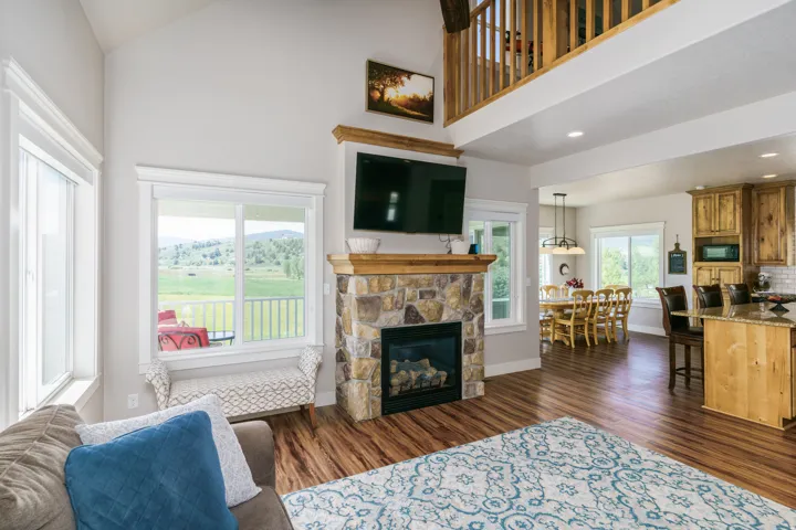 Vaulted ceilings enhance the living area, featuring a stone fireplace with a wood mantle
