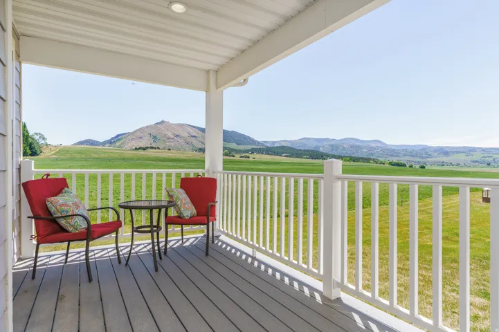 Covered porch with composite decking, white railing, recessed lighting, and expansive mountain scenery