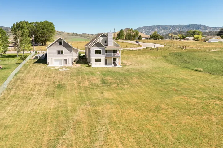 Expansive property featuring two distinct structures, a large grassy area, and distant mountainous terrain