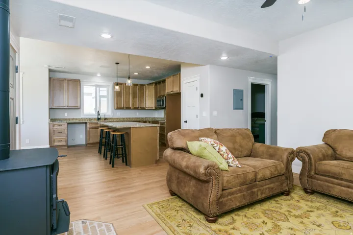 Open-concept living area featuring wood-finish flooring, a wood-burning stove with brick surround, and recessed lighting