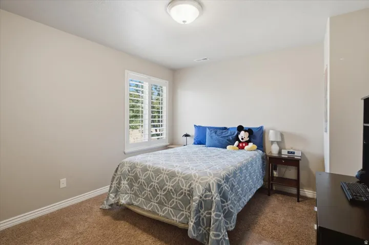 Recessed window with white plantation shutters, neutral wall color, built-in ceiling light fixture, and textured carpeting