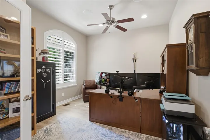 Arched window with plantation shutters, wood-finish flooring, recessed lighting, and a ceiling fan
