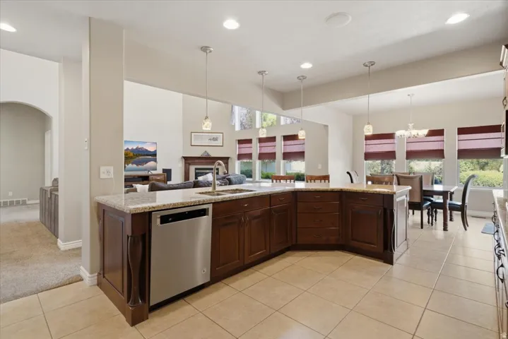 Kitchen island featuring an undermount sink, stainless steel dishwasher, and granite countertop