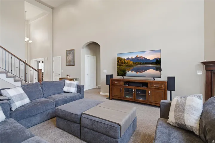 Two-story ceiling, arched doorway, staircase with wood handrail and metal balusters, and a built-in media console