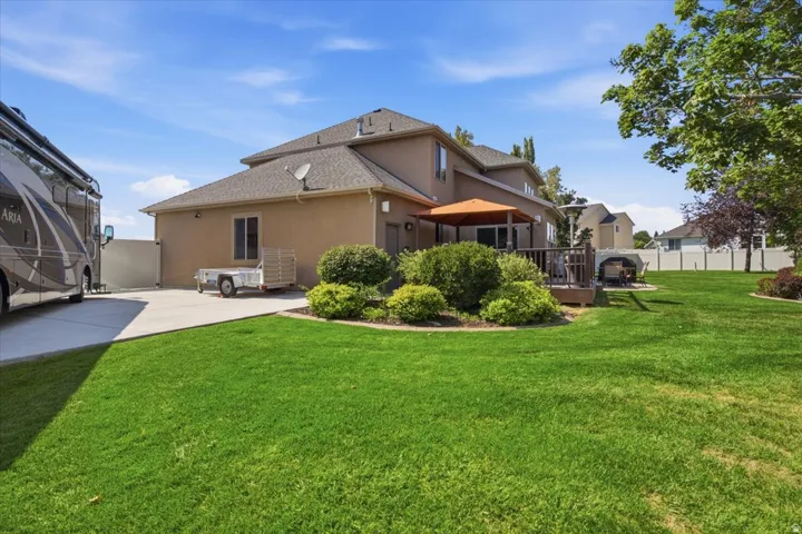 Expansive lawn area with a multi-level deck, built-in outdoor fireplace, and mature landscaping