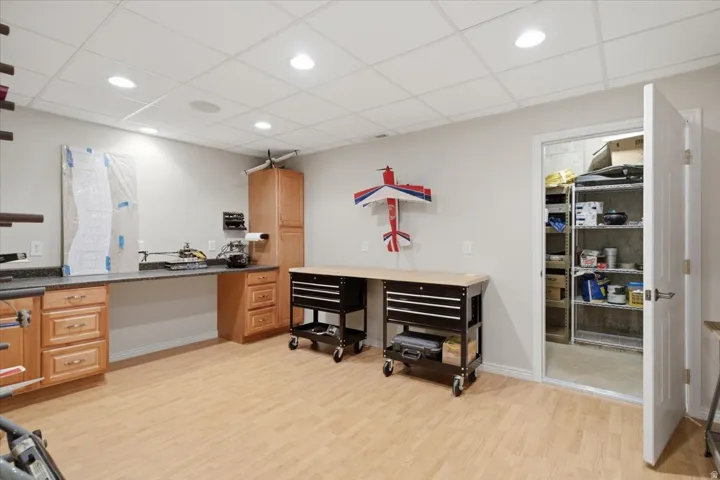 Recessed ceiling lighting, wood-finish flooring, built-in cabinetry, durable countertop, and additional storage with metal shelving