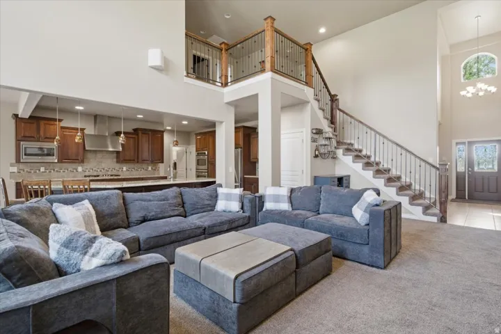 Two-story foyer with decorative arched window, grand staircase with wrought iron balusters, hardwood handrail, and open-concept living area with vaulted ceilings
