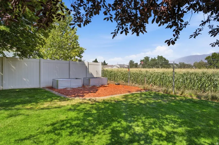 Expansive lawn area with a perimeter fence, two galvanized raised garden beds, and a decorative ground cover