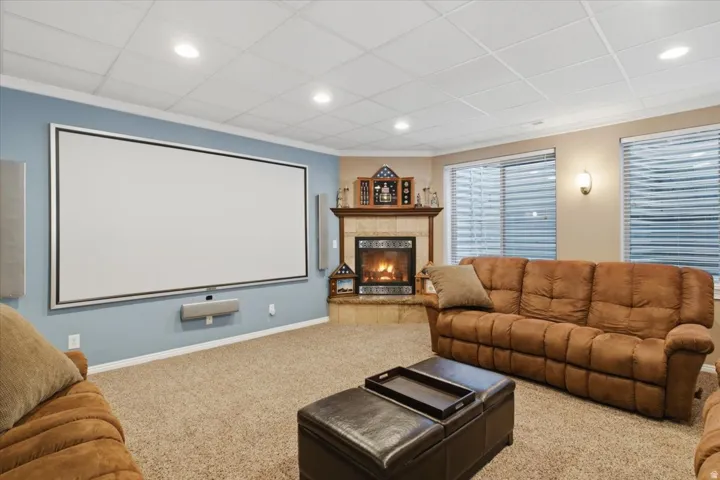 Built-in projection screen, gas fireplace with tile surround, wood mantel, recessed lighting, and soft carpeting