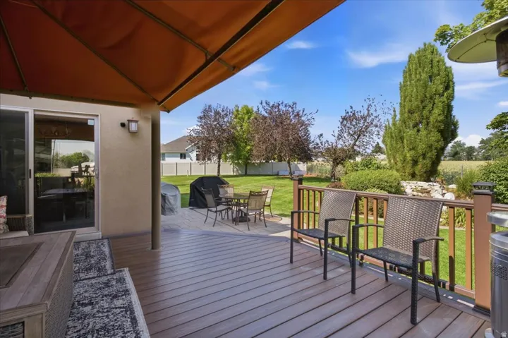 Expansive outdoor living area featuring a composite deck, a lower paver patio, and a privacy railing with built-in lighting