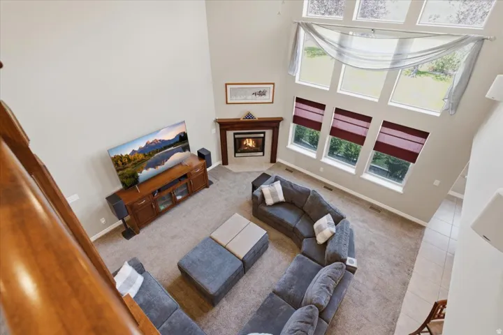 Two-story living area with high ceilings, large windows, and a corner fireplace with a wood mantle