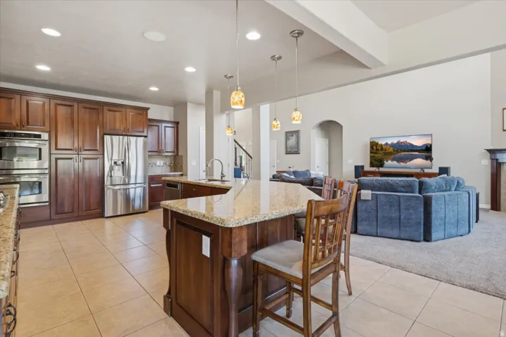 Kitchen featuring rich wood cabinetry, stainless steel appliances, a center island with bar seating, tile flooring, and recessed lighting