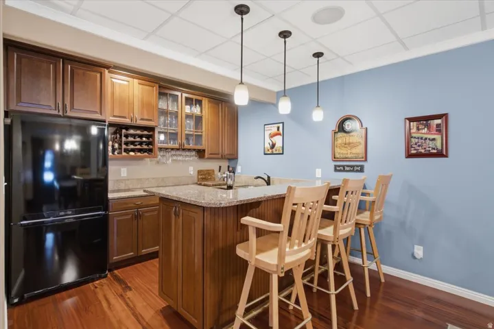 Wood-finish flooring, built-in cabinetry, integrated wine storage, granite countertops, and modern pendant lighting