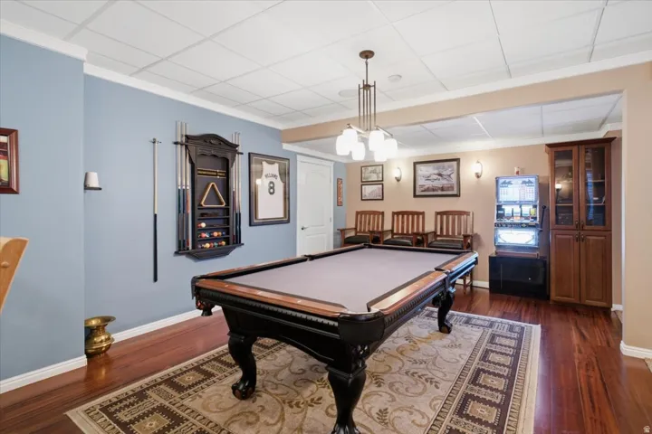 Hardwood flooring, drop ceiling, built-in cabinetry, wall sconces, and a multi-light chandelier
