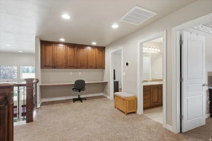 Built-in desk with overhead cabinetry, recessed lighting, carpet flooring, and white paneled doors