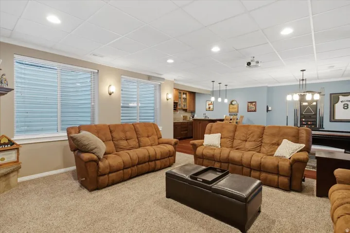 Recessed lighting, wood-finish flooring, built-in wet bar with cabinetry, drop ceiling, and wall sconces