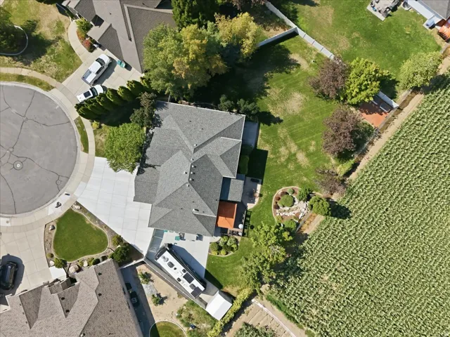 Multi-pitch roofline, expansive concrete driveway, cul-de-sac location, manicured lawn, and established landscaping