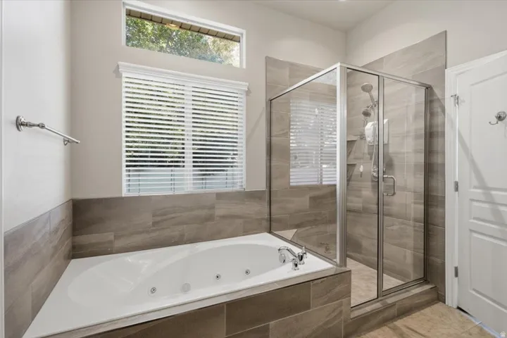 Built-in jetted tub, glass-enclosed shower, and full-height tile surround