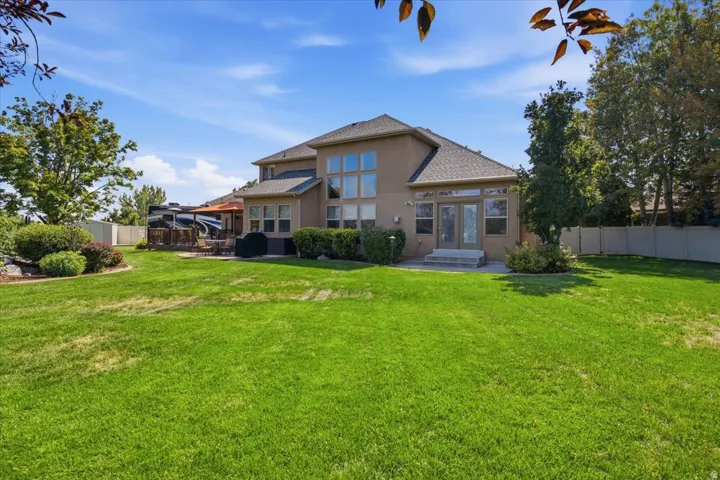 Expansive lawn with mature landscaping, a multi-level deck, and a private patio space