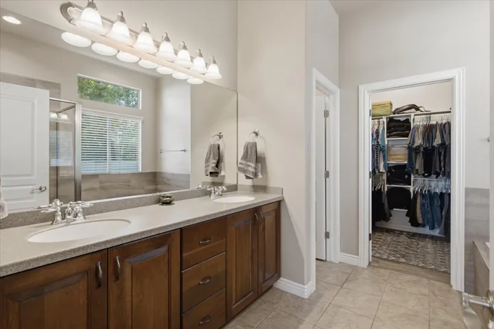 Dual vanity with undermount sinks, wood-finish cabinetry, and a large mirror