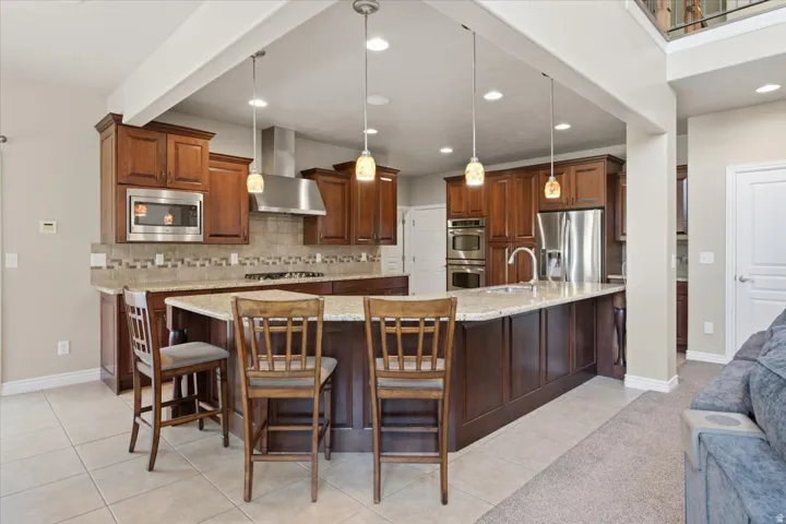 Spacious kitchen featuring rich wood cabinetry, stainless steel appliances, a large center island with seating, and pendant lighting