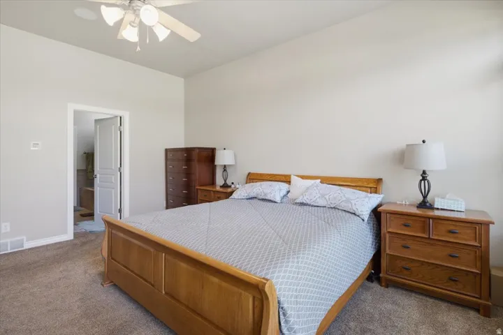 Carpeted flooring, vaulted ceiling, ceiling fan, and painted walls