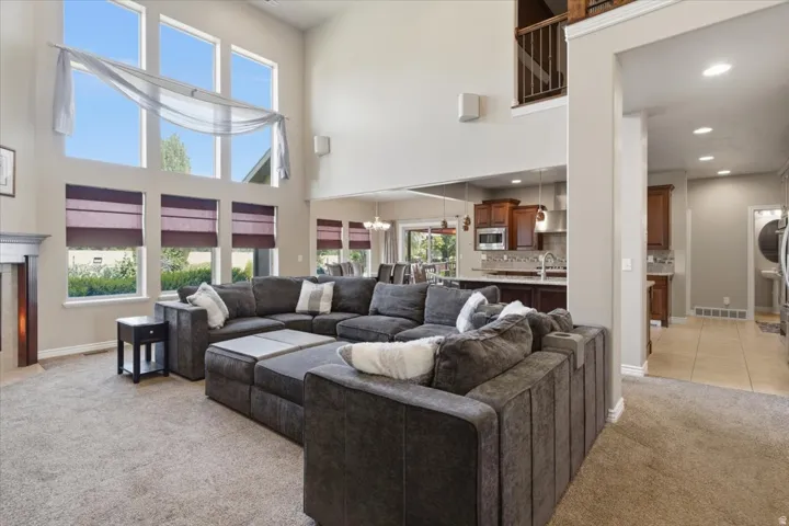 Two-story living area with high ceilings, large windows featuring custom window treatments, and a built-in fireplace