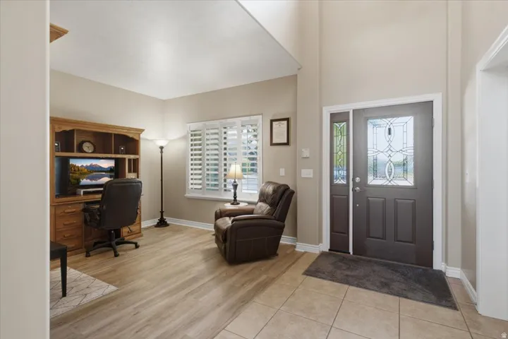 Entry foyer featuring a decorative glass panel door with a sidelight, tile flooring, and a vaulted ceiling