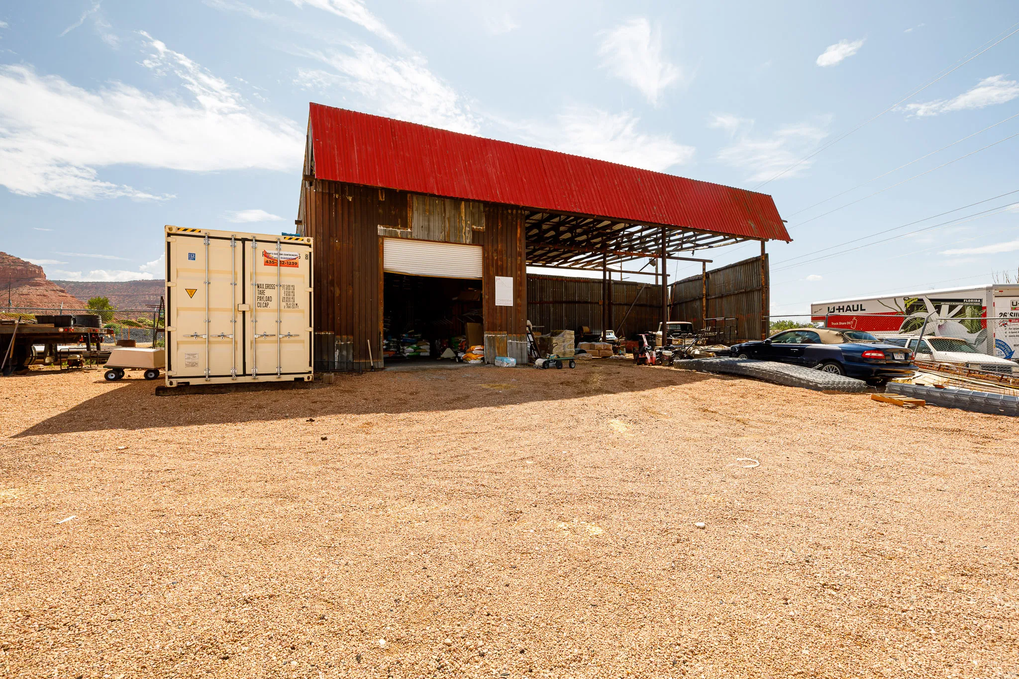 Barn structure with a red corrugated metal roof and open-sided storage area