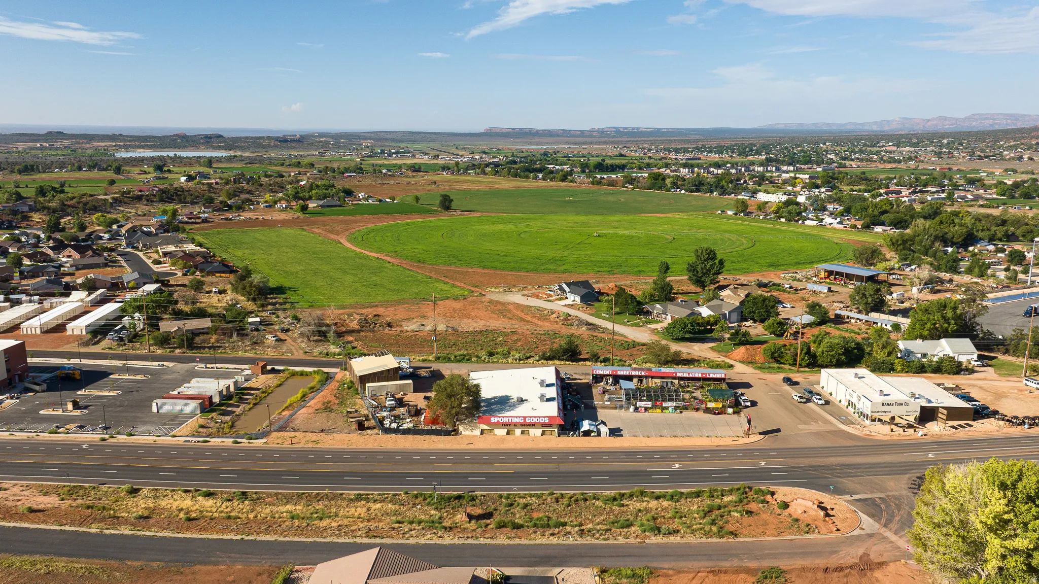 Expansive land parcel featuring existing commercial buildings, a substantial paved parking area, and direct road frontage