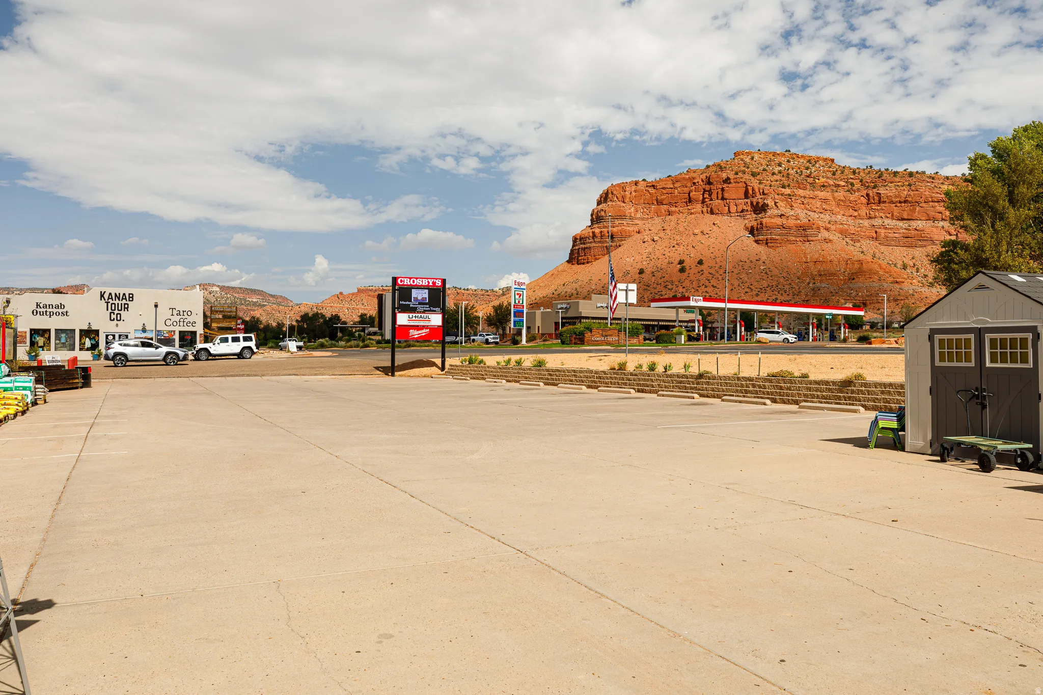 Expansive paved surface with surrounding commercial establishments, framed by distant mountains