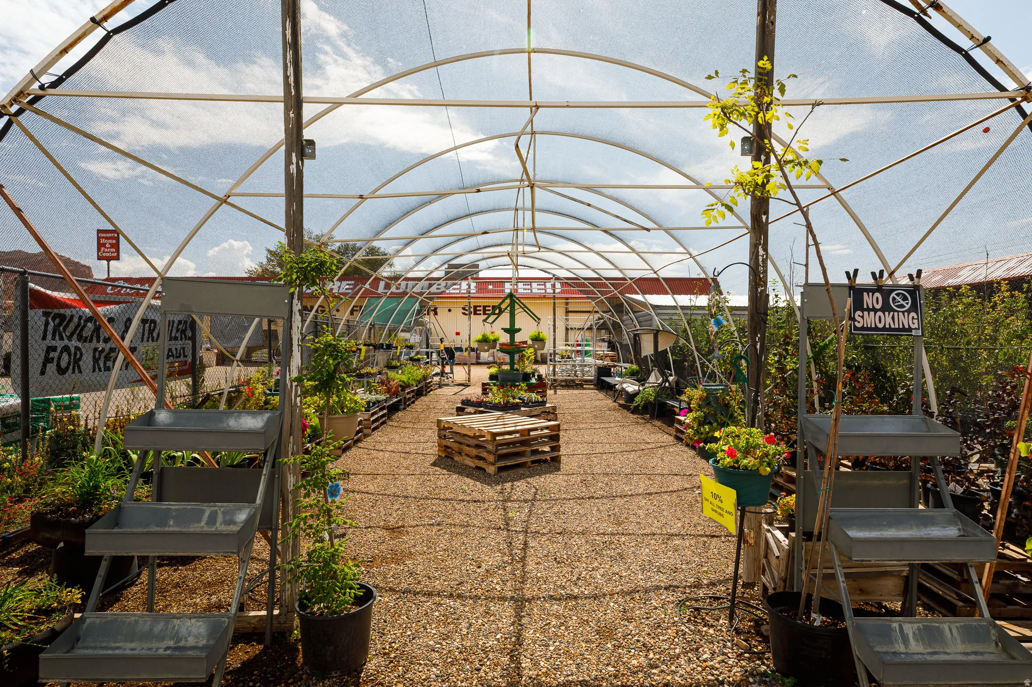 Open-air structure with arched framework, gravel pathway, and multiple display shelves