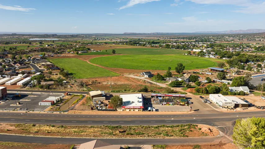 Expansive land parcel featuring existing commercial buildings, a substantial paved parking area, and direct road frontage